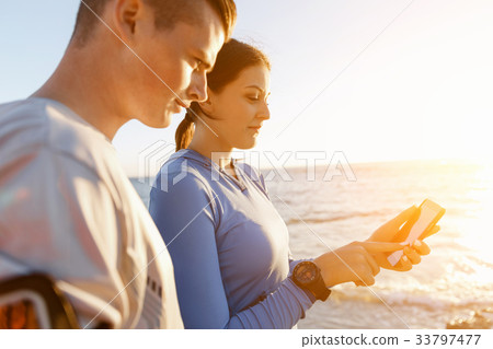 Young couple with smartphones outdoors Young couple with smartphones outdoors 33797477