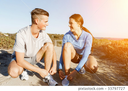 Couple of runners lace their shoes and prepare to jogging 33797727