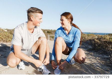 Couple of runners lace their shoes and prepare to jogging 33797729