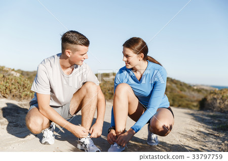 Couple of runners lace their shoes and prepare to jogging Couple of runners lace their shoes and prepare to jogging 33797759