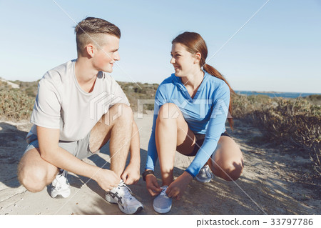 Couple of runners lace their shoes and prepare to jogging 33797786