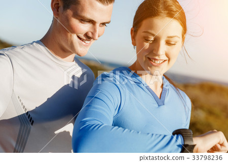 Runner woman with heart rate monitor running on beach 33798236