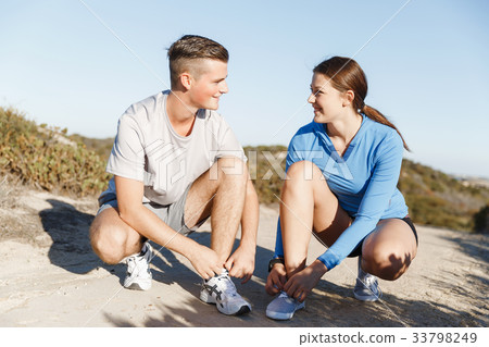 Couple of runners lace their shoes and prepare to jogging Couple of runners lace their shoes and prepare to jogging 33798249
