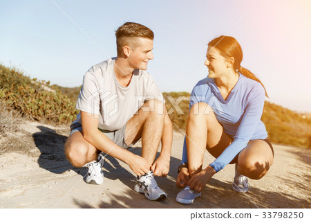 Couple of runners lace their shoes and prepare to jogging 33798250