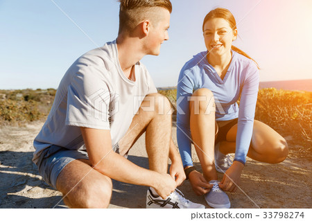 Couple of runners lace their shoes and prepare to jogging 33798274