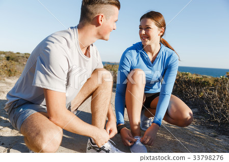 Couple of runners lace their shoes and prepare to jogging Couple of runners lace their shoes and prepare to jogging 33798276