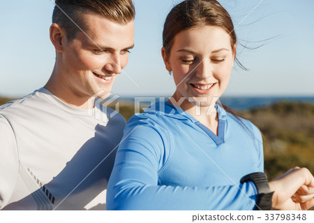 Runner woman with heart rate monitor running on beach 33798348