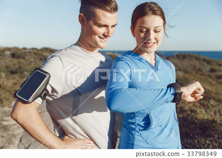 Runner woman with heart rate monitor running on beach 33798349