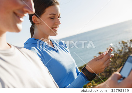 Young couple with smartphones outdoors Young couple with smartphones outdoors 33798559
