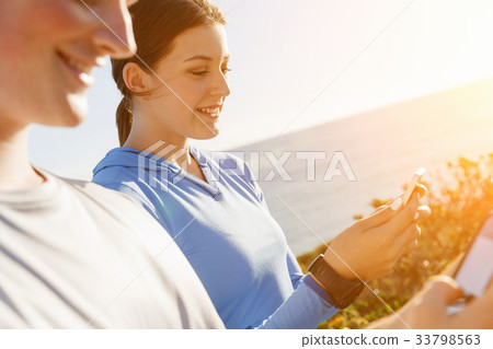 Young couple with smartphones outdoors Young couple with smartphones outdoors 33798563