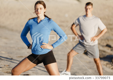 Young couple on beach training together Young couple on beach training together 33799073