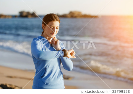 Runner woman with heart rate monitor running on beach Runner woman with heart rate monitor running on beach 33799138