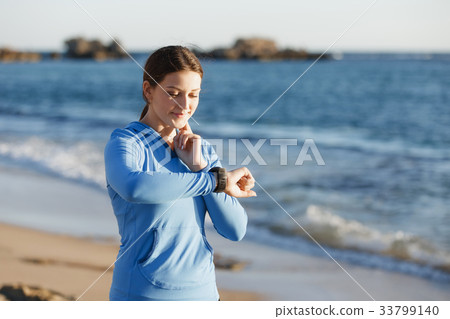 Runner woman with heart rate monitor running on beach Runner woman with heart rate monitor running on beach 33799140