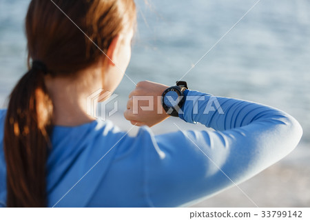 Runner woman with heart rate monitor running on beach 33799142