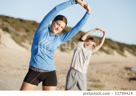 Young couple on beach training together Young couple on beach training together 33799424