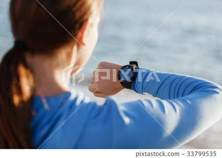 Runner woman with heart rate monitor running on beach 33799535