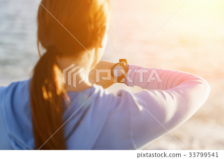 Runner woman with heart rate monitor running on beach Runner woman with heart rate monitor running on beach 33799541