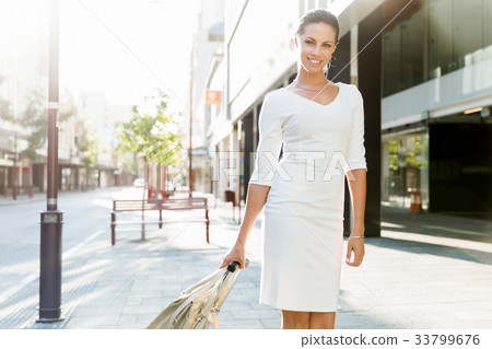 Business woman pulling suitcase bag walking in city Business woman pulling suitcase bag walking in city 33799676