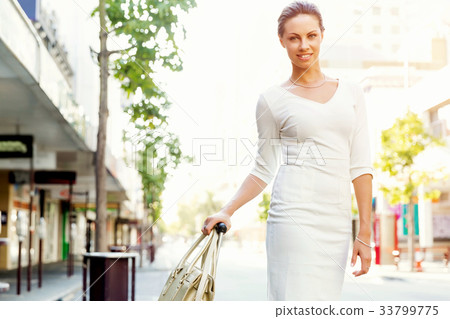 Business woman pulling suitcase bag walking in city 33799775