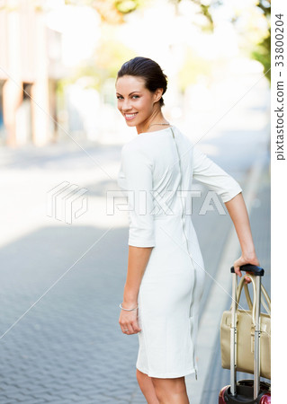 Business woman pulling suitcase bag walking in city 33800204