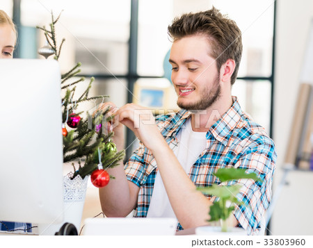 Portrait of smiling office worker with little Christmas tree 33803960