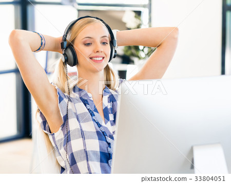 Young woman working in office with headphones 33804051