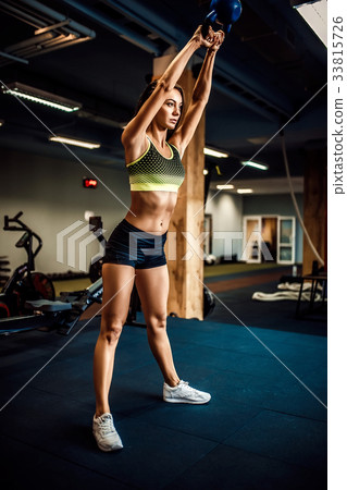 Attractive female athlete performing a kettle-bell 33815726