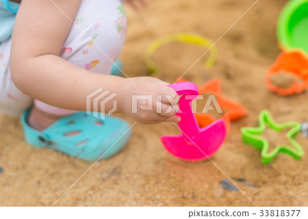 Kid hand playing with plastic toy in sand box Kid hand playing with plastic toy in sand box 33818377