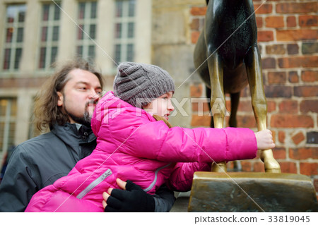Little tourist touching famous statue in the center of Bremen known as Bremen Town Musicians Little tourist touching famous statue in the center of Bremen known as Bremen Town Musicians 33819045