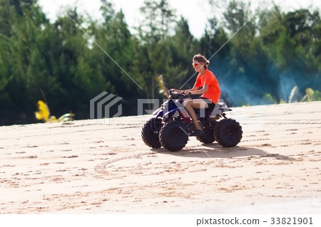 Teenager riding quad bike on beach Teenager riding quad bike on beach 33821901
