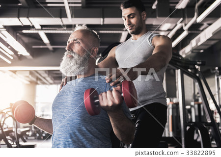 Concentrated senior male is training his biceps in 33822895