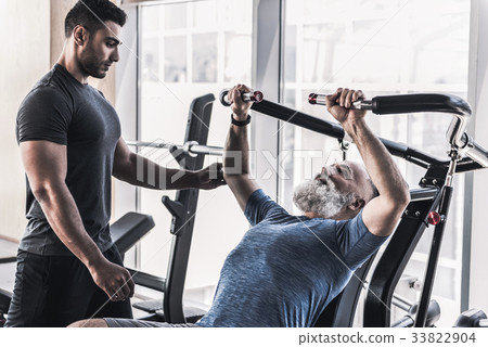 Concentrated old male is having workout with his Concentrated old male is having workout with his 33822904