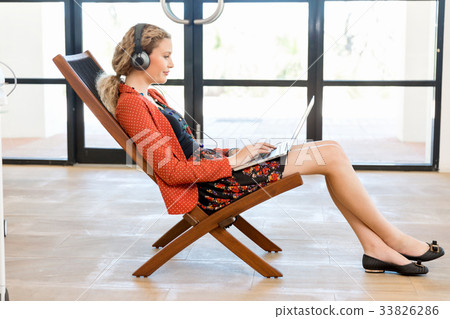 Young woman listening to the music while working on a computer Young woman listening to the music while working on a computer 33826286