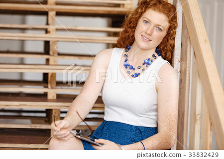 Portrait of young woman sitting at the stairs in office 33832429