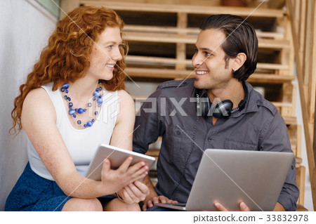 Portrait of two young people sitting at the stairs in office Portrait of two young people sitting at the stairs in office 33832978