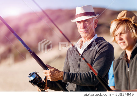 Senior man fishing with his grandson Senior man fishing with his grandson 33834949