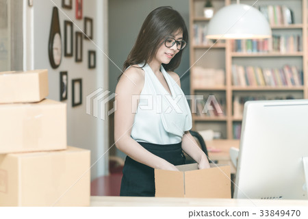 Young entrepreneur packing product into the box Young entrepreneur packing product into the box 33849470