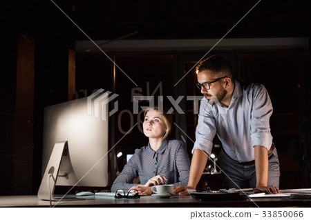 Businesspeople in the office at night working late Businesspeople in the office at night working late 33850066