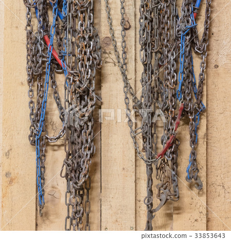 Old snow chains hanging in a barn 33853643
