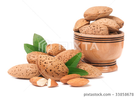 Almonds in a wooden bowl with leaves isolated on Almonds in a wooden bowl with leaves isolated on 33858678