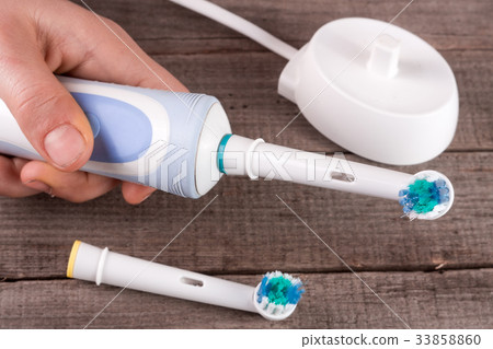 Electric Toothbrush in hand on an old wooden Electric Toothbrush in hand on an old wooden 33858860