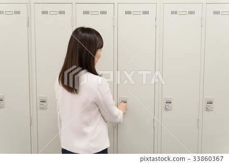 Female employee opening locker Female employee opening locker 33860367