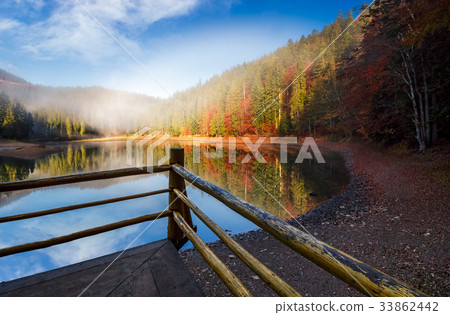 wooden pierce fence on a lake in fog 33862442