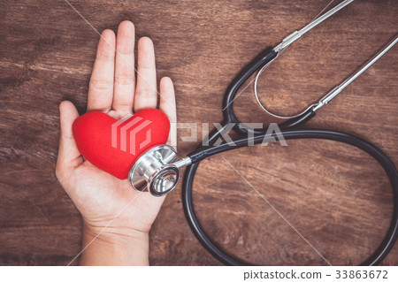 Red heart on woman hand with doctor's stethoscope Red heart on woman hand with doctor's stethoscope 33863672