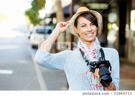 Outdoor summer smiling lifestyle portrait of pretty young woman with camera Outdoor summer smiling lifestyle portrait of pretty young woman with camera 33864713