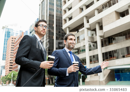 Two young businessmen hailing for a taxi Two young businessmen hailing for a taxi 33865483