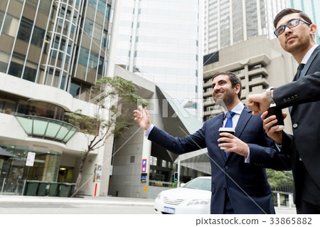 Two young businessmen hailing for a taxi 33865882