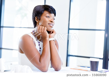 Young woman sitting at a desk in an office and working on blueprint 33868090