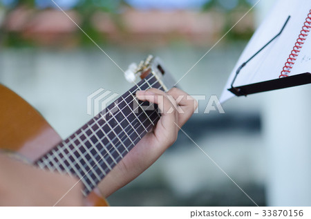 The children play the classic guitar happily. 33870156