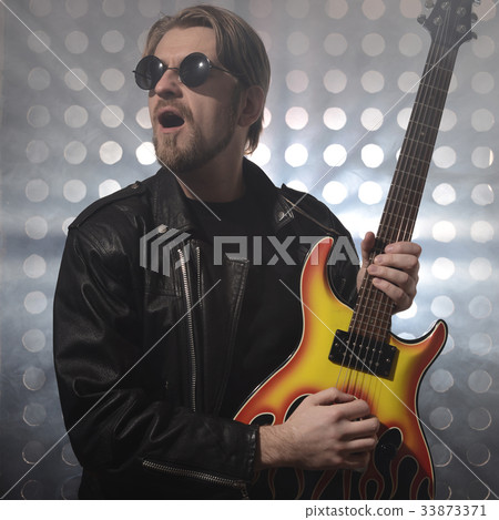 Attractive bearded man plays guitar in smoke Attractive bearded man plays guitar in smoke 33873371